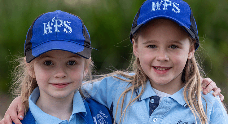 Two girls with arms over each other's shoulders.
